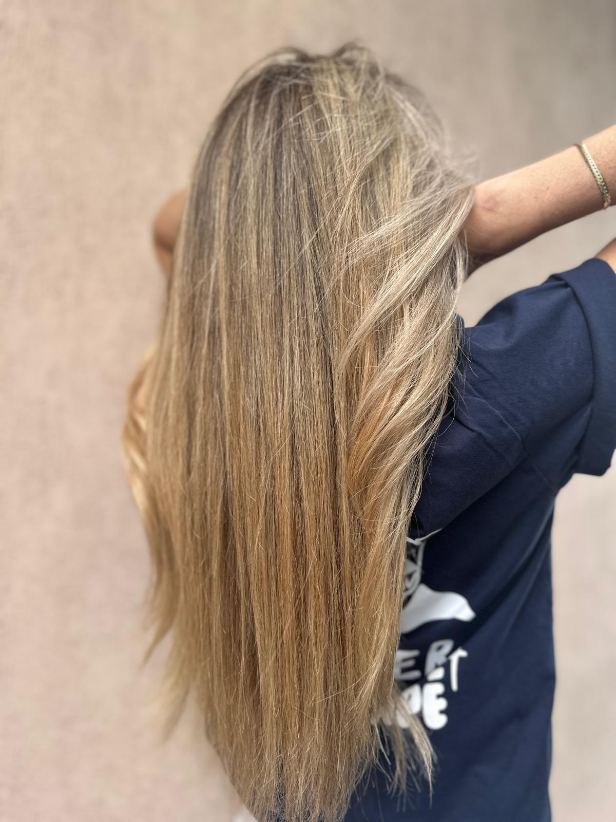 Person with long, straight blonde hair viewed from behind against a plain background.