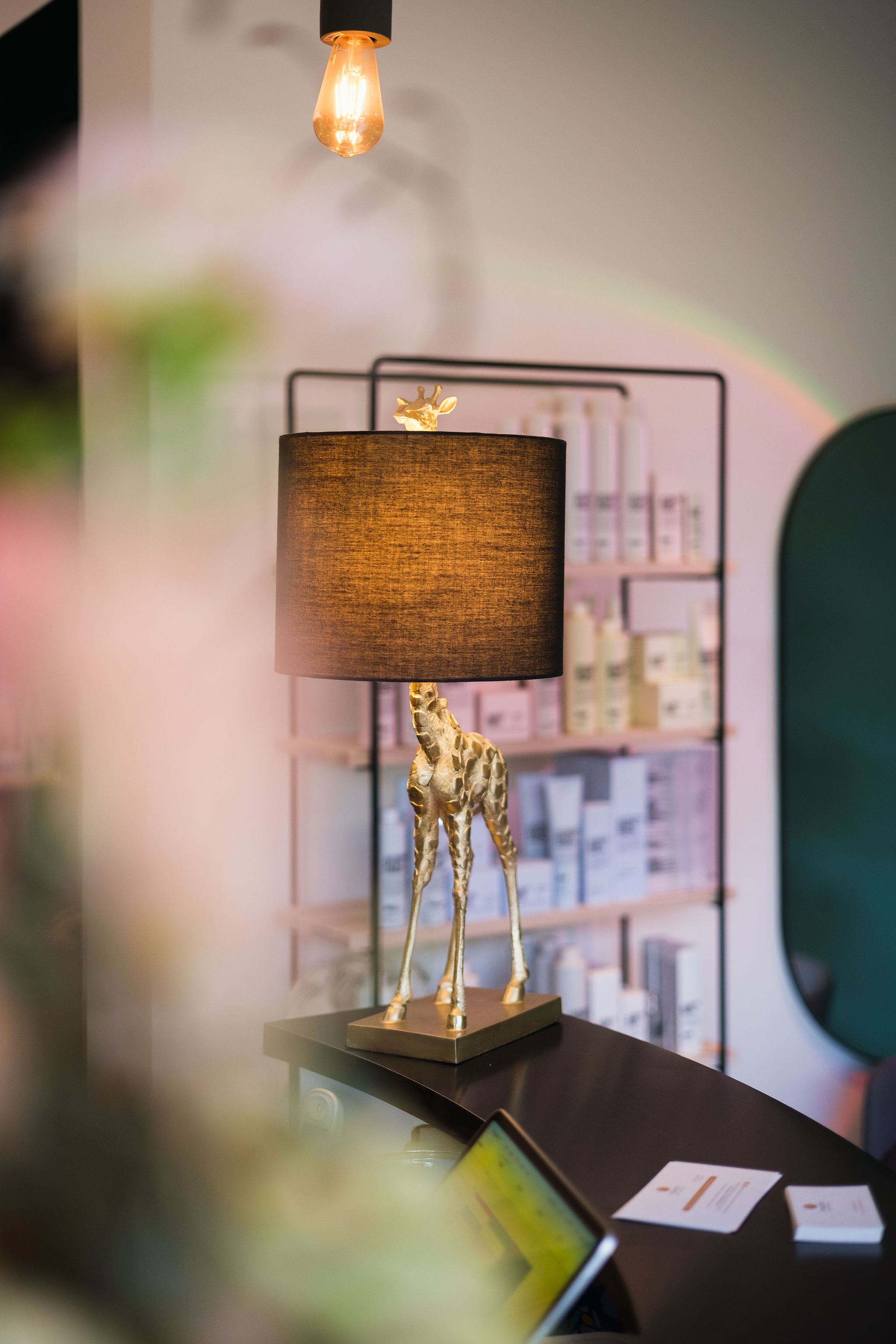 Decorative lamp with a golden giraffe base and brown lampshade on a desk in a softly lit room.